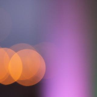 An abstract pattern of lights: orange circles next to a violet and green vertical band