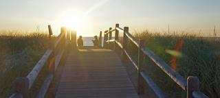 A bridge to Ferry Beach and two people having conversation while sun rises.