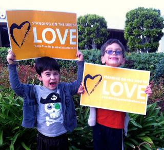 Children, smiling, hold signs for the Standing on the Side of Love campaign.