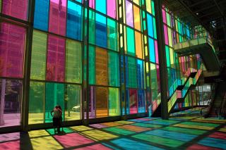 Sunlight shines through multicolored rectangular windows casting colorful shadows on the floor.
