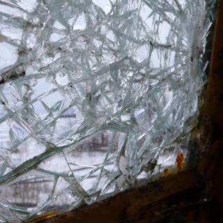 A thick pane of glass is shattered, with hundreds of radiating cracks