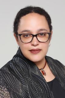 headshot of the Rev. Dr. Sofía Betancourt, wearing dark glasses, a red necklace with a red pendant, and dark gray patterned blouse