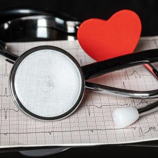Stethoscope and paper heart laying on an ekg readout