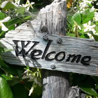 Wood welcome sign surrounded by foliage