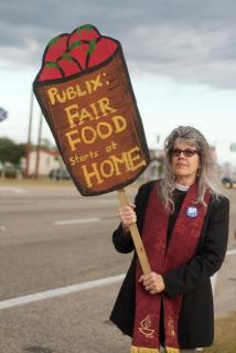 Rev. Amy Carol Webb, River of Grass UU Congregation, Davie, FL, witnesses for worker justice, holding Fair Food starts at Home sign.